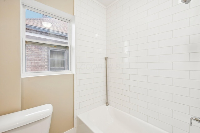 bathroom featuring tiled shower / bath combo and toilet