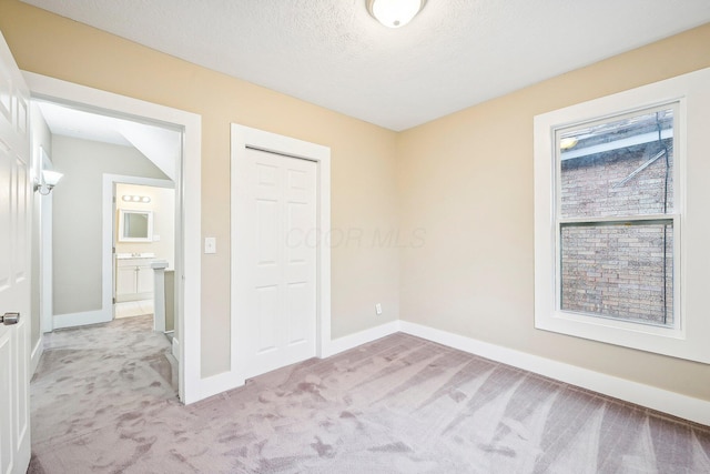 unfurnished bedroom with a textured ceiling, light colored carpet, and a closet