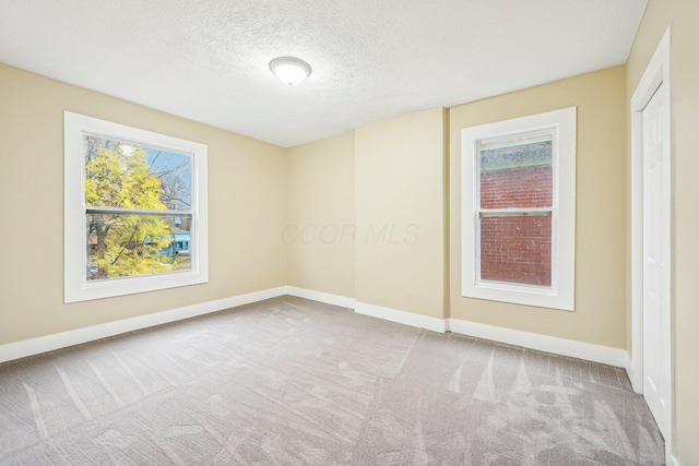 empty room featuring a textured ceiling and light carpet