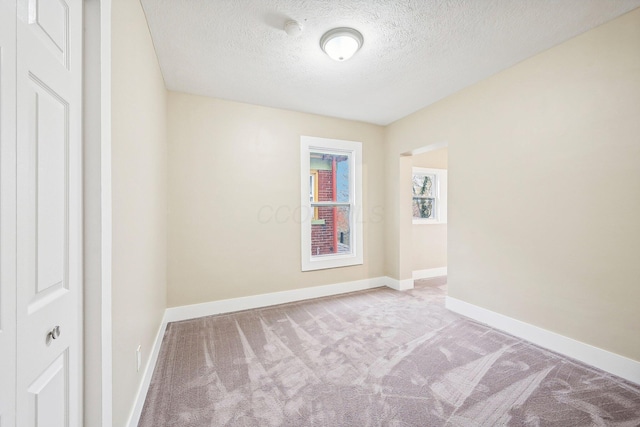 carpeted empty room with a textured ceiling