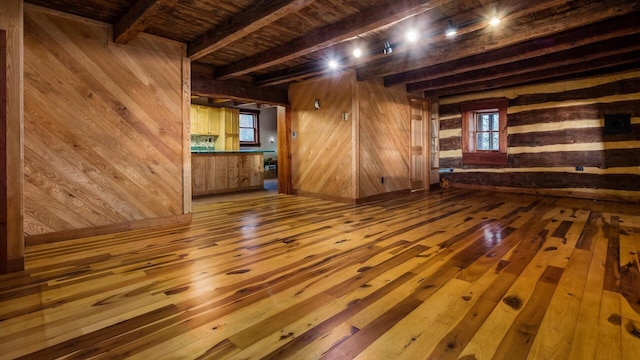 unfurnished living room with hardwood / wood-style floors, a wealth of natural light, and wood walls