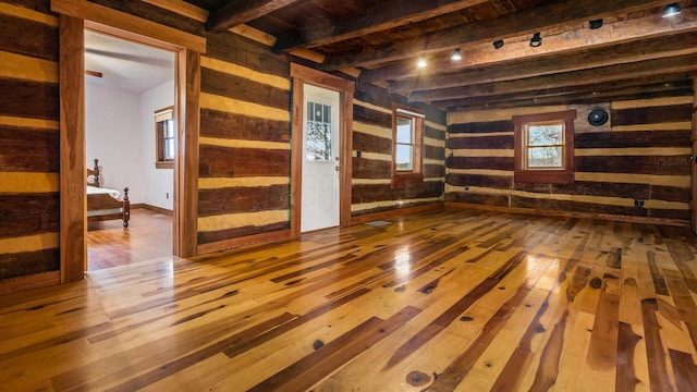 spare room featuring beam ceiling, wooden walls, and hardwood / wood-style flooring