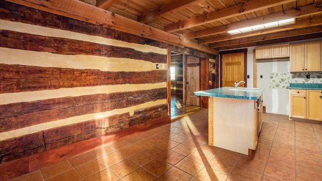 kitchen featuring light brown cabinets, tile patterned flooring, beamed ceiling, a center island with sink, and wood ceiling