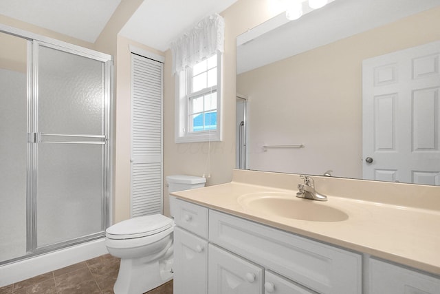 bathroom with tile patterned flooring, vanity, a shower with shower door, and toilet