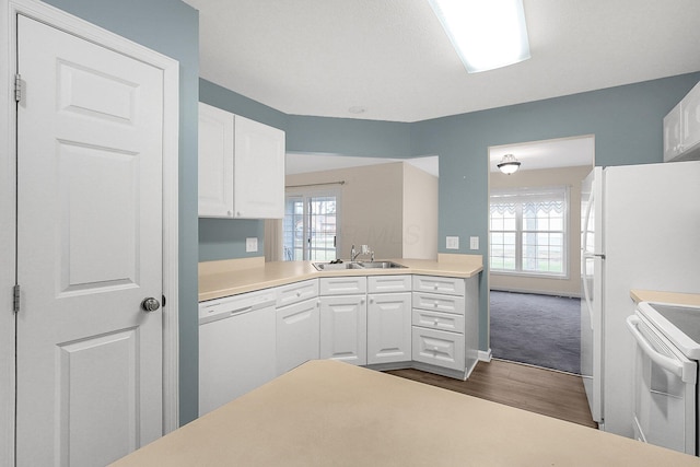 kitchen with white appliances, dark colored carpet, sink, white cabinetry, and kitchen peninsula