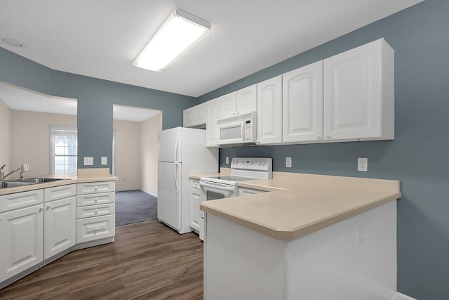 kitchen with kitchen peninsula, white cabinetry, sink, and white appliances