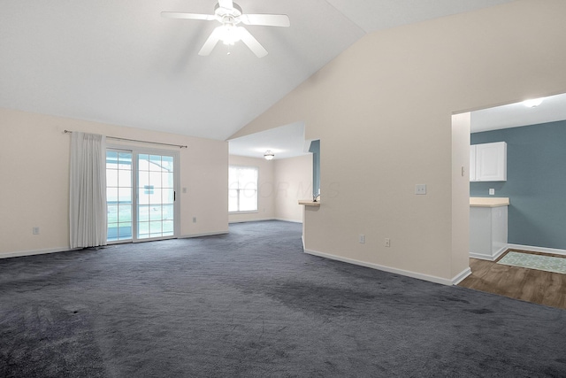 empty room with dark colored carpet, ceiling fan, and high vaulted ceiling