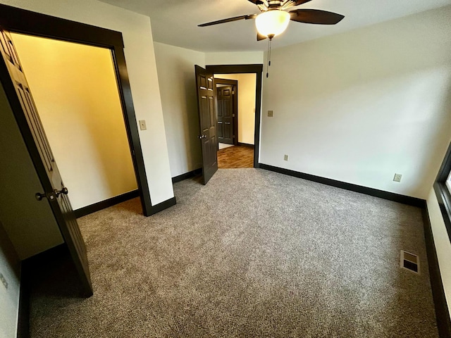 unfurnished bedroom with ceiling fan and dark colored carpet