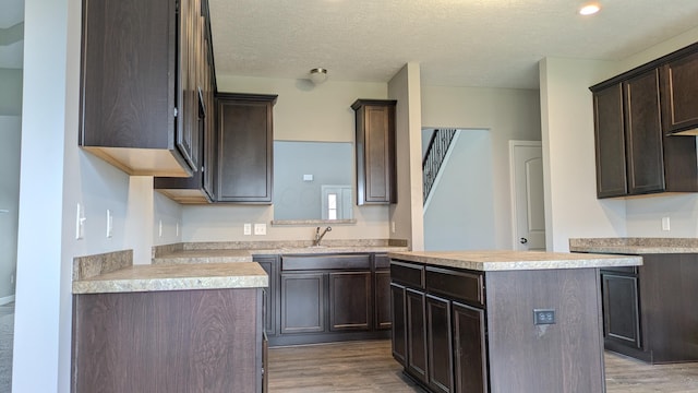 kitchen featuring light wood-type flooring, a center island, and dark brown cabinetry