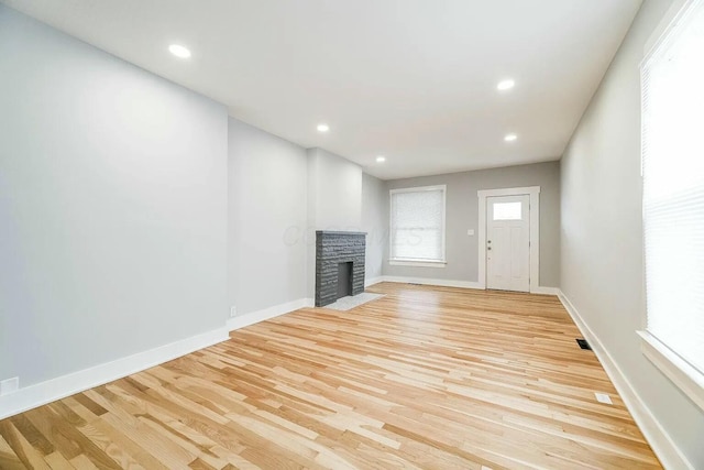 unfurnished living room featuring a brick fireplace and light wood-type flooring