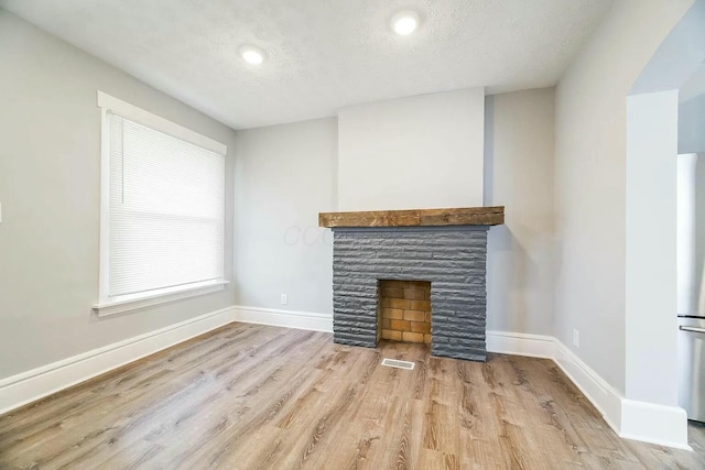 unfurnished living room featuring a textured ceiling, light hardwood / wood-style floors, and a fireplace