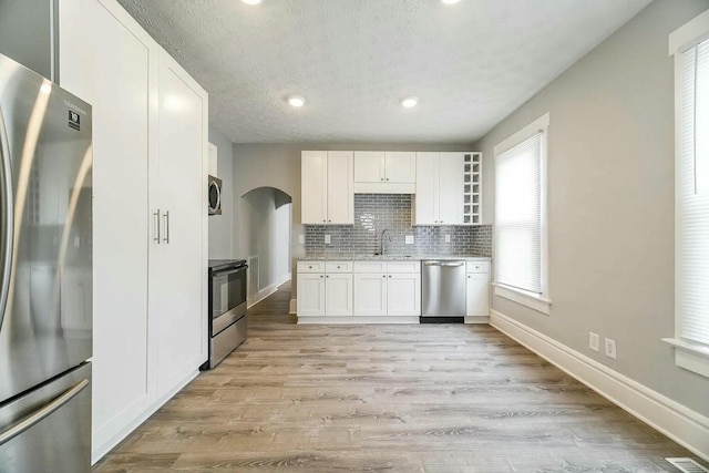 kitchen featuring sink, white cabinets, light wood-type flooring, and appliances with stainless steel finishes