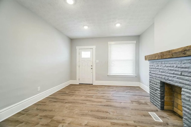 foyer with a fireplace, a textured ceiling, and light hardwood / wood-style floors