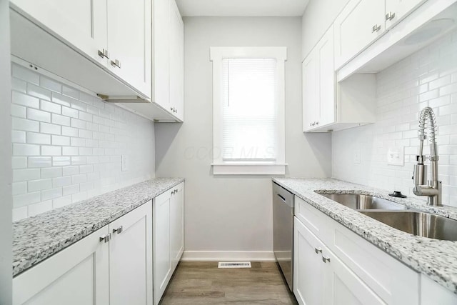 kitchen with white cabinets, sink, stainless steel dishwasher, light stone counters, and dark hardwood / wood-style flooring