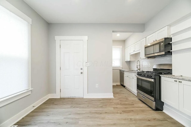 kitchen featuring white cabinets, sink, light hardwood / wood-style floors, light stone counters, and stainless steel appliances