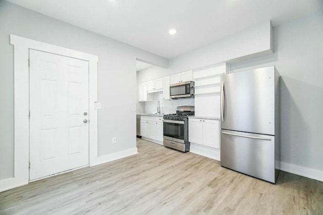 kitchen featuring light wood-type flooring, backsplash, stainless steel appliances, sink, and white cabinets