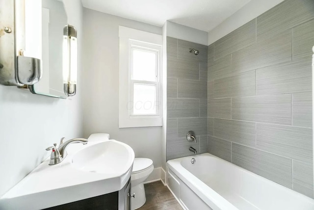 full bathroom with vanity, wood-type flooring, tiled shower / bath combo, and toilet