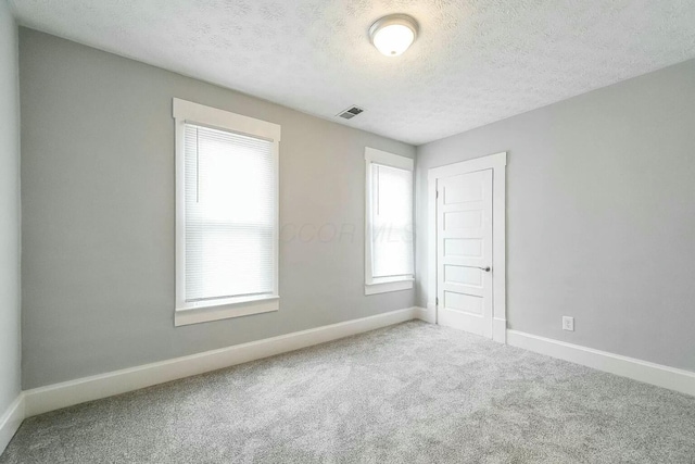 carpeted empty room with a textured ceiling