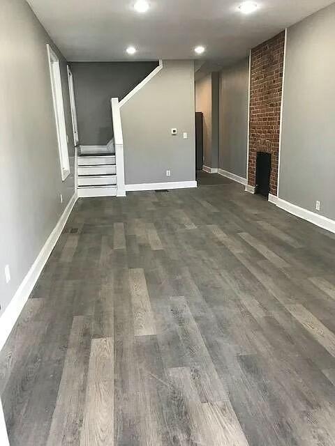 unfurnished living room featuring a fireplace and dark wood-type flooring