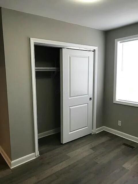 unfurnished bedroom featuring a closet and dark hardwood / wood-style floors