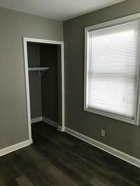 unfurnished bedroom with a closet and dark hardwood / wood-style floors