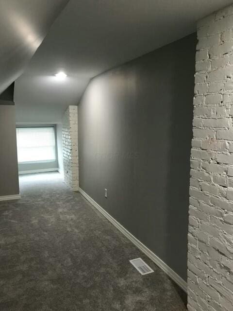 interior space with lofted ceiling and brick wall