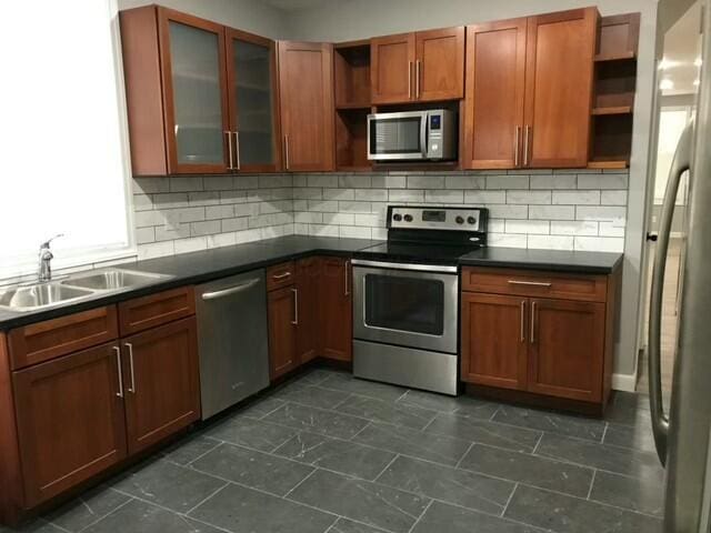 kitchen featuring decorative backsplash, sink, dark tile patterned floors, and appliances with stainless steel finishes