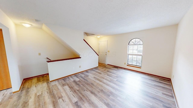 unfurnished living room with light wood-type flooring and a textured ceiling