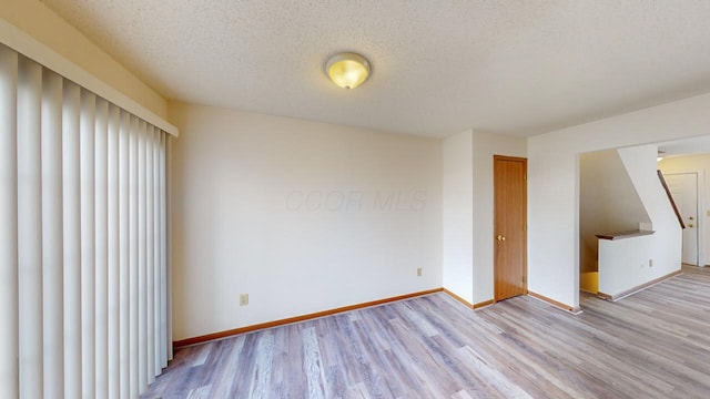 empty room with a textured ceiling and light wood-type flooring