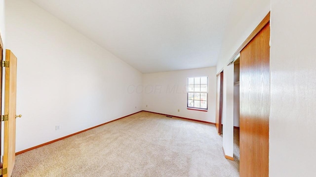 unfurnished bedroom featuring light carpet and a closet