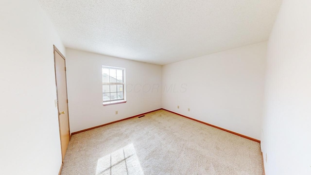 carpeted spare room featuring a textured ceiling