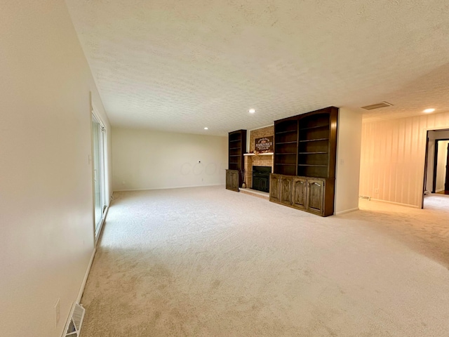 unfurnished living room featuring light colored carpet, a textured ceiling, and a brick fireplace