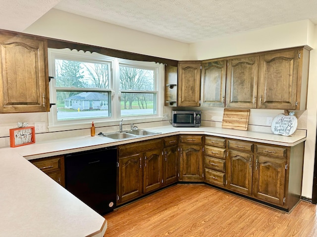 kitchen featuring a textured ceiling, sink, black dishwasher, and light hardwood / wood-style flooring