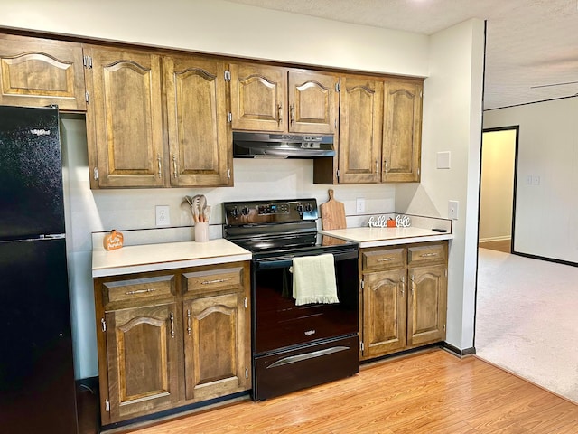 kitchen with a textured ceiling, light hardwood / wood-style flooring, and black appliances