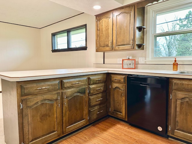 kitchen with kitchen peninsula, dishwasher, a healthy amount of sunlight, and light hardwood / wood-style floors