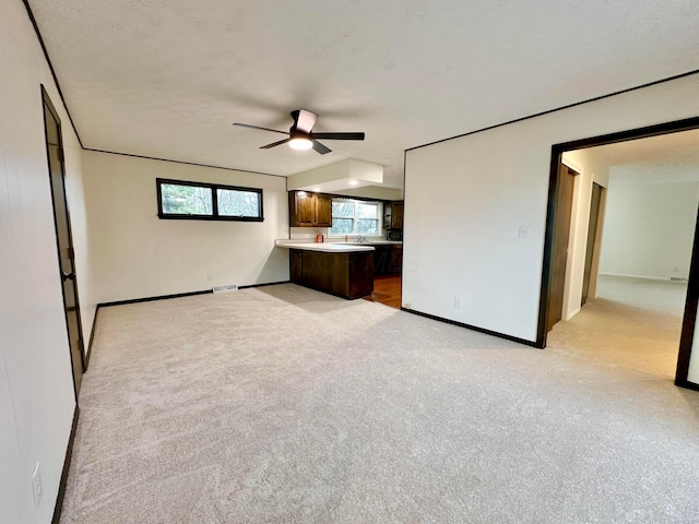 unfurnished living room featuring light colored carpet and a textured ceiling