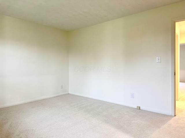 spare room featuring light carpet and a textured ceiling