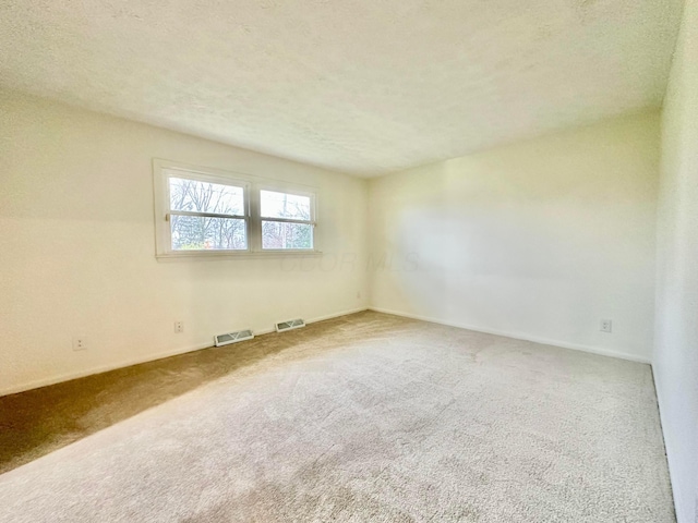 carpeted spare room with a textured ceiling