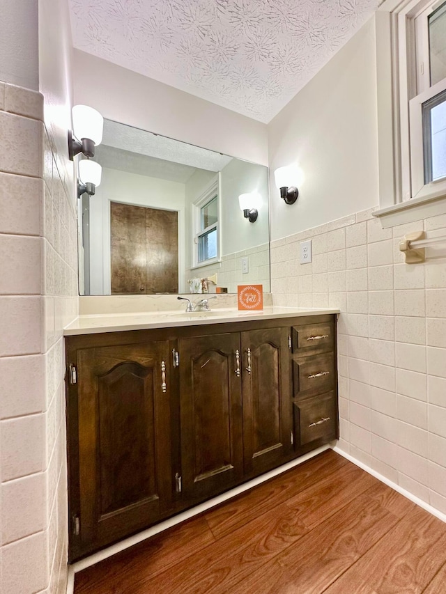 bathroom with a textured ceiling, vanity, hardwood / wood-style flooring, and tile walls