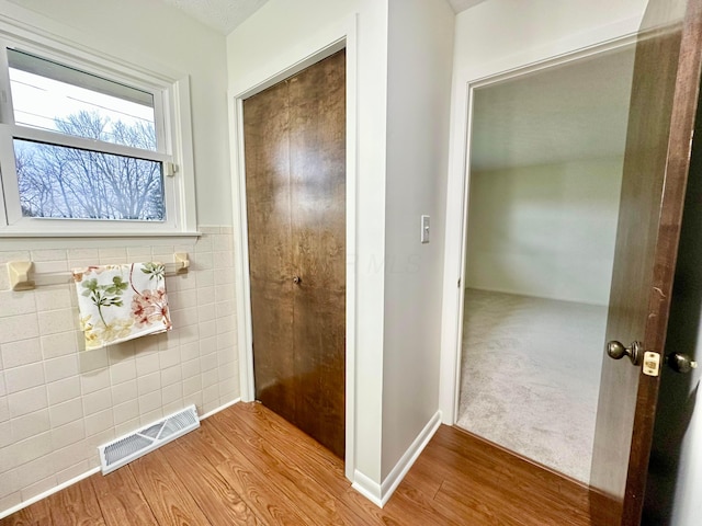 hall featuring light hardwood / wood-style flooring and tile walls