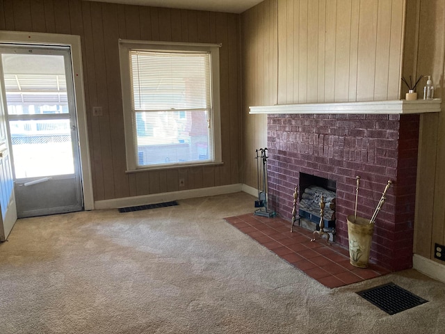 unfurnished living room featuring a fireplace, carpet flooring, and wood walls