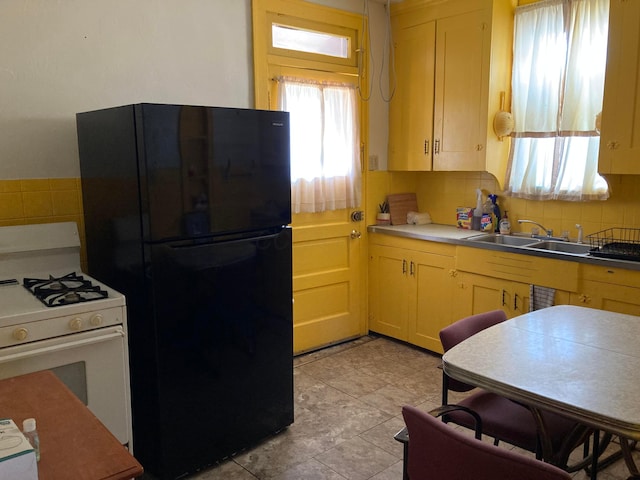 kitchen with black refrigerator, white gas range, and sink