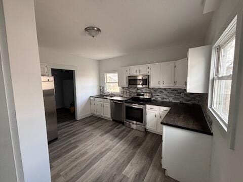 kitchen with backsplash, dark hardwood / wood-style flooring, white cabinets, and stainless steel appliances