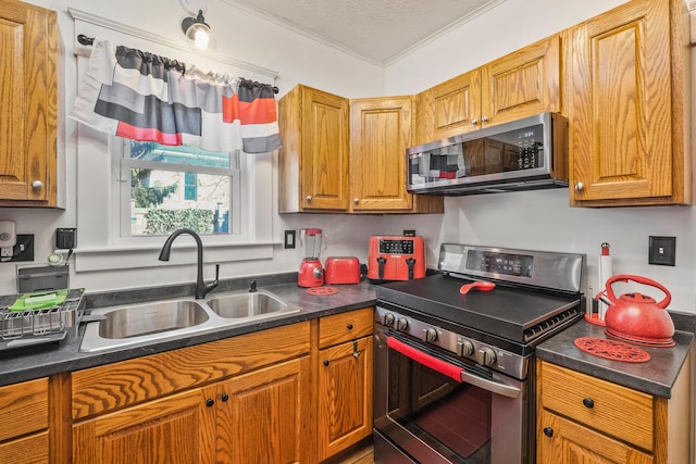 kitchen with appliances with stainless steel finishes, a textured ceiling, ornamental molding, and sink