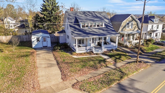 view of front of home featuring a porch and a storage shed