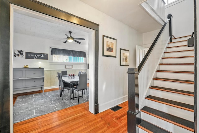 stairs featuring hardwood / wood-style flooring and ceiling fan