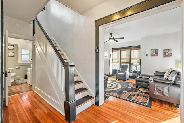 staircase featuring a healthy amount of sunlight, ceiling fan, and wood-type flooring