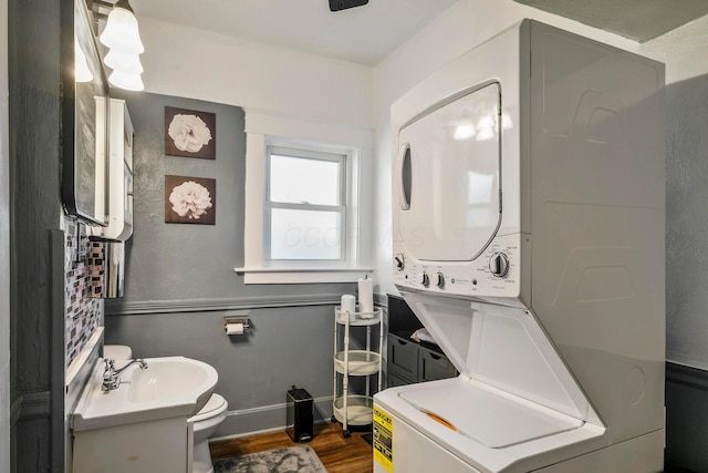 bathroom featuring wood-type flooring, vanity, toilet, and stacked washer and clothes dryer