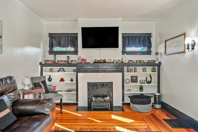 living room with hardwood / wood-style floors and a brick fireplace