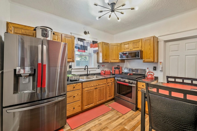 kitchen with a textured ceiling, sink, stainless steel appliances, and light hardwood / wood-style flooring